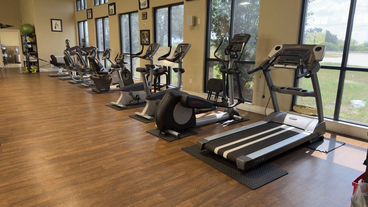 Row of treadmills, recumbent bikes and ellipticals along the windows at Castroville Physical Therapy